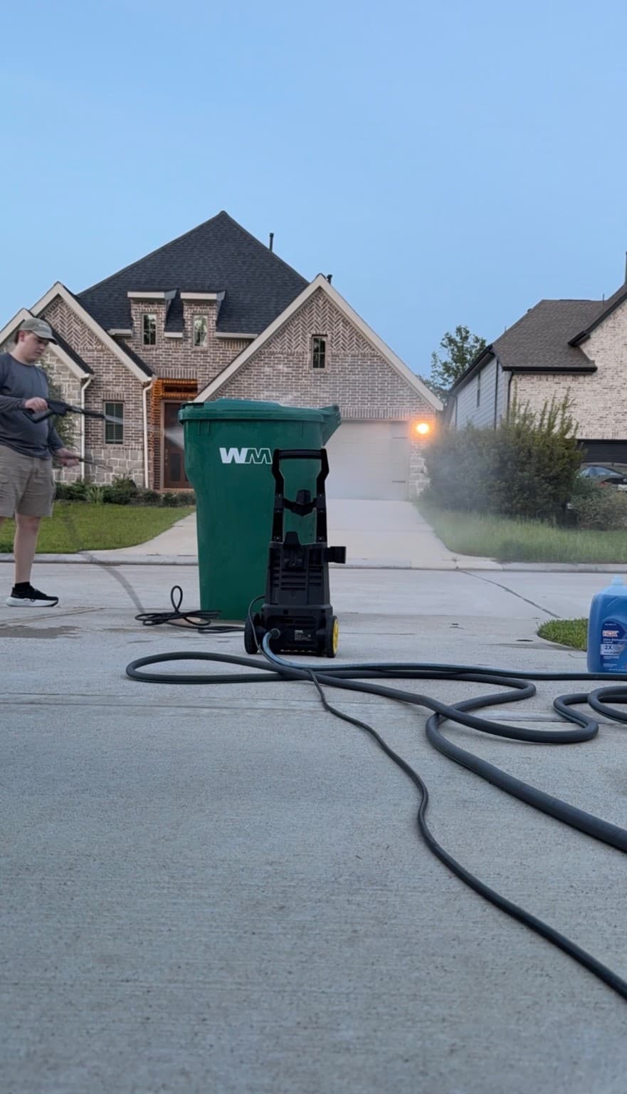 Xterior Cleaning Xperts pressure washing a trash can at the curb in front of a home